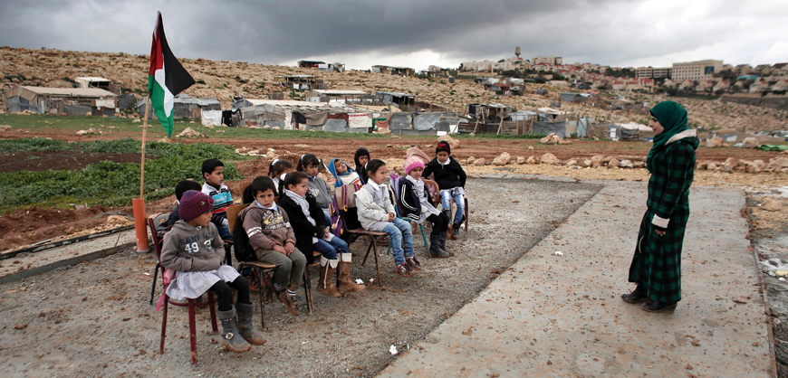A Palestinian teacher leads a class of Palestinian bedouin children from the Abu Anwar community near the Jewish settlement of Maale Adumim (background), in the West Bank city of Al Azariya, east of Jerusalem, on Wednesday (AFP photo)